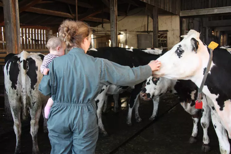 Agricultrice avec son enfant devant ses vaches laitières