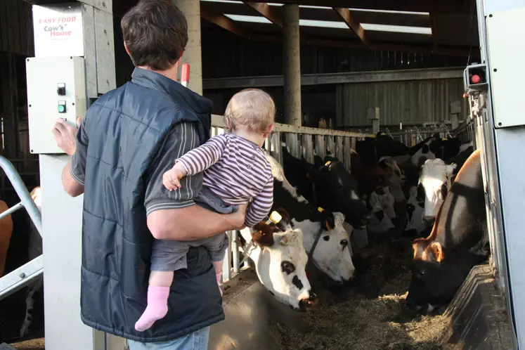 Agriculteur et son enfant dans la ferme devant des vaches
