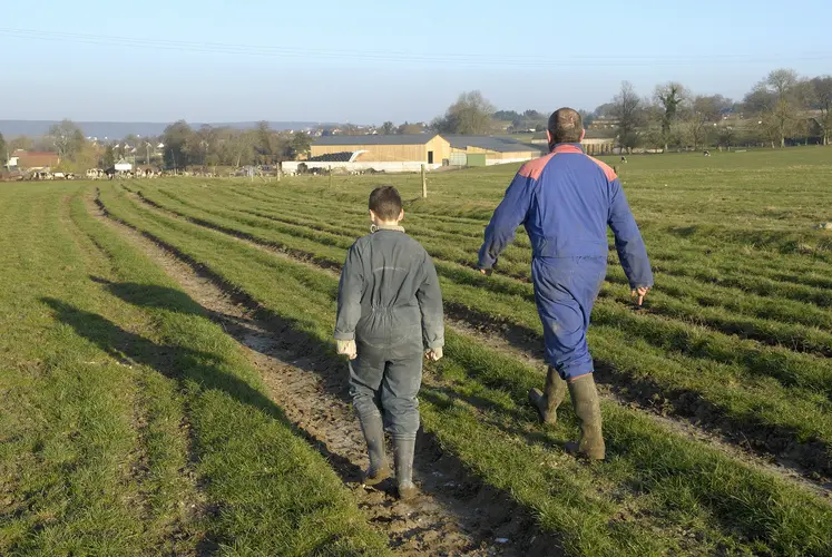 Un homme et un enfant en tenue d'agriculteur marchent dans un champ