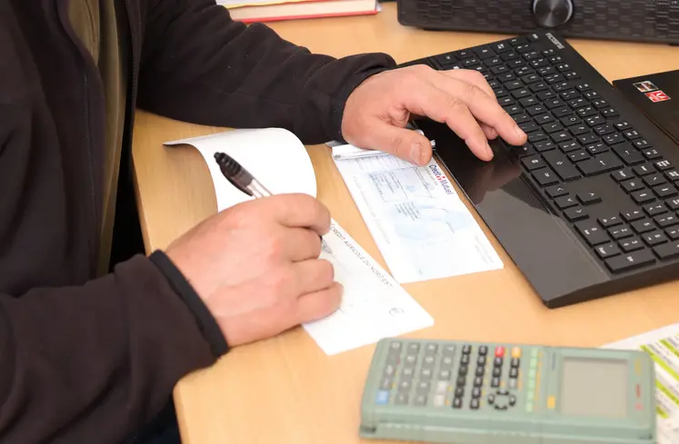 Vigneron contrôlant sa trésorerie en espèces et effectuant un paiement par cheque.