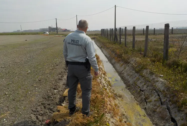 Agent de l'OFB devant un fossé bordant un champ