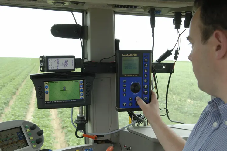 Agriculteur au volant de son tracteur devant le tableau de commande du pulvérisateur. 