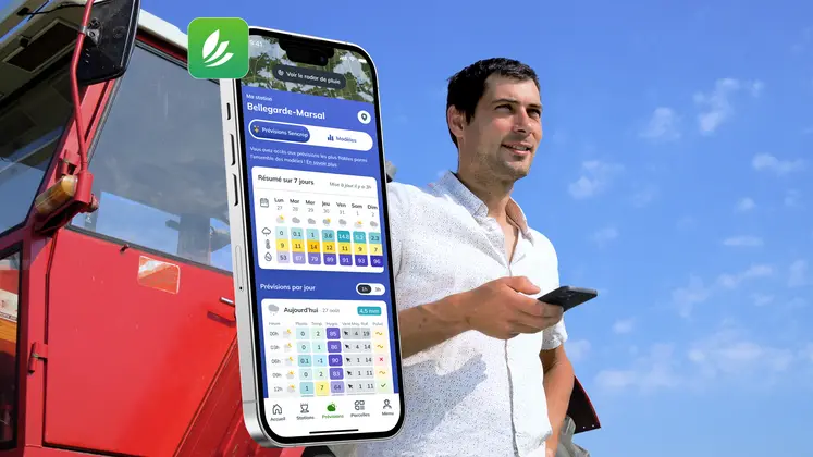 homme tenant un smartphone devant un tracteur dans un champ