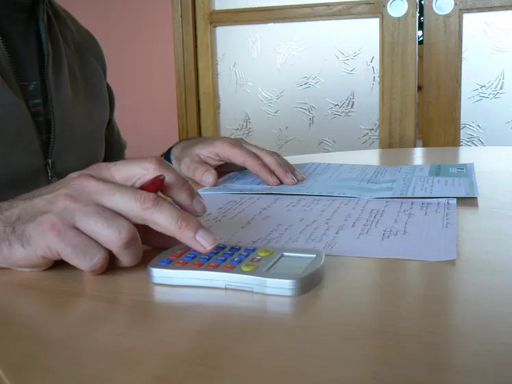 Agriculteur devant un bureau avec une calculatrice