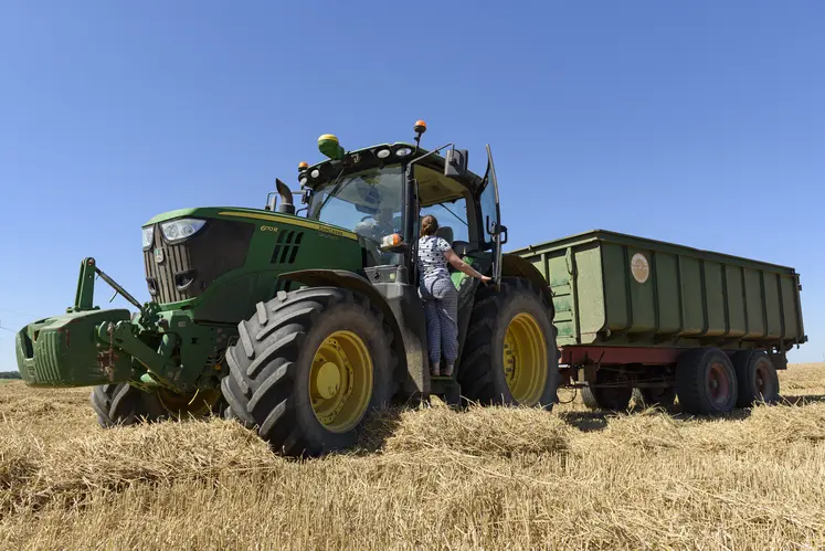 Jeune agricultrice montant dans un tracteur en période de moisson