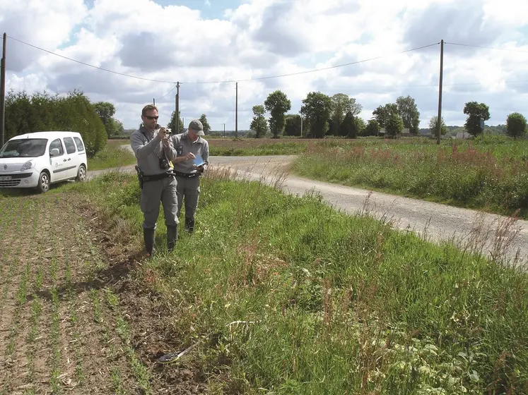 deux agents de l'OFB en bordure de champ à côté d'une route