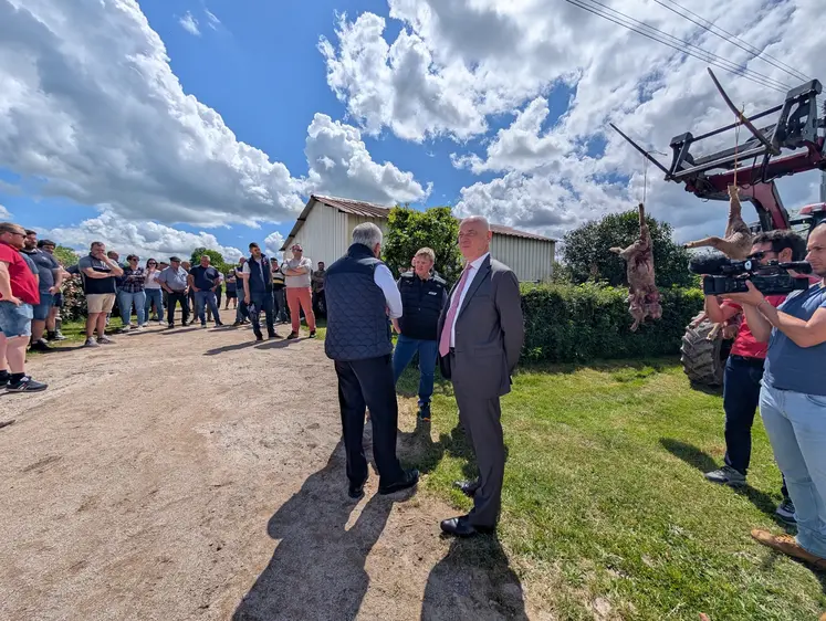 Le préfet de Saône-et-Loire discutant avec une éleveuse devant deux carcasses de moutons suspendues à un tracteur.