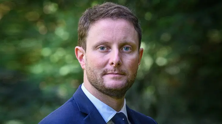 Clément Beaune, Haut-Commissaire à la stratégie et au plan, en gros plan devant un fond de verdure.