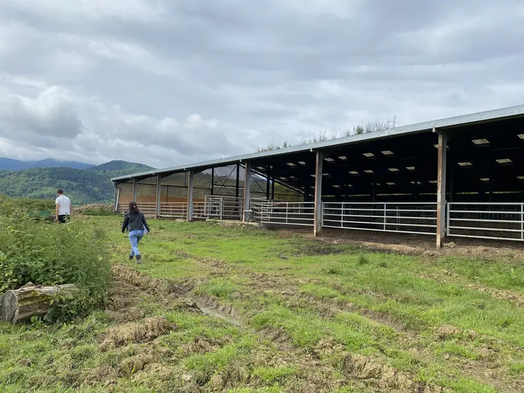 Deux personnes passant devant un hangar agricole