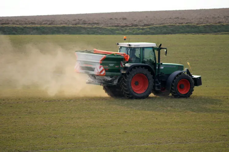 Un tracteur épand un engrais azoté (ammonitrate) sur un champ de céréales.
