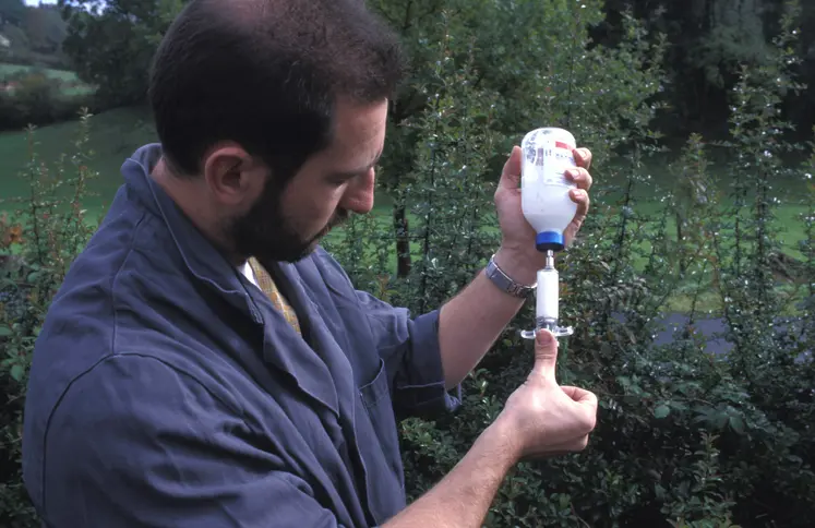 Vétérinaire réalisant un prélèvement dans un flacon d'antibiotique sur une exploitation bovine.