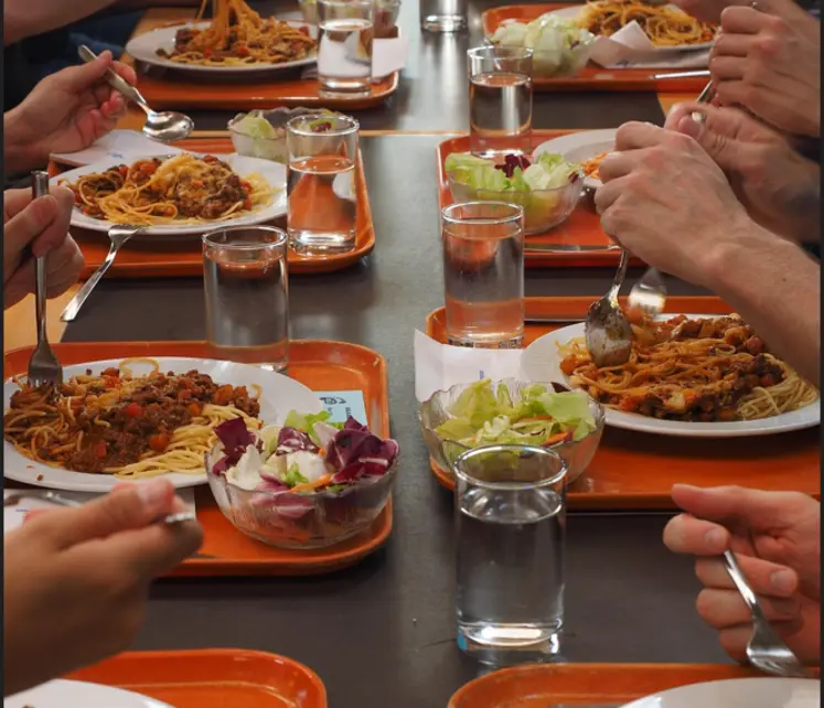 restauration collective gros plan sur une table avec des personnes en train de manger