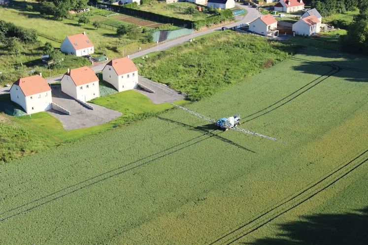 vue aérienne de maisons bordant des champs traités pas un tracteur 
