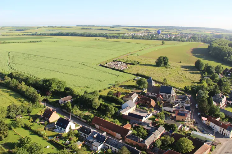 Photographie aérienne d'un paysage rural avec une exploitation agricole, un village et des champs 