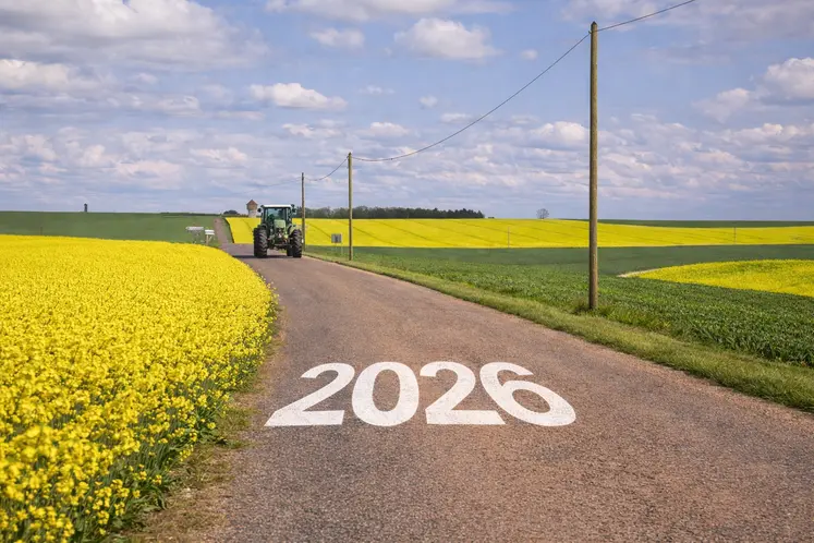  Tracteur sur une route de campagne entourée de champs de colza avec l’inscription 2026 sur la route.  