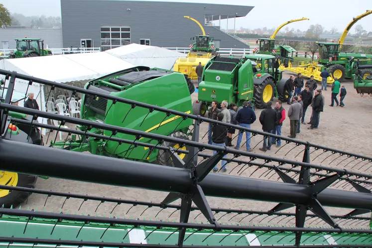 Visiteurs dans un concessionnaire John Deere devant des machines agricoles. 