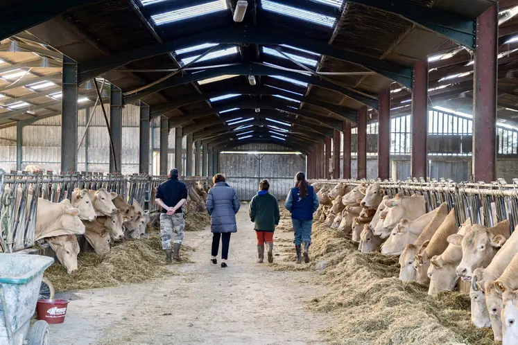 Annie Genevard de dos avec des éleveurs dans une stabulation 