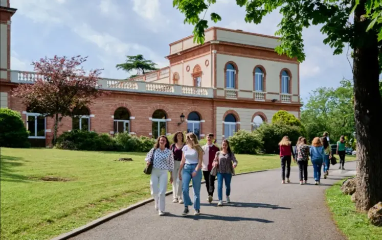 des élèves marchent sur une allée avec un bâtiment en briques en arrière-plan