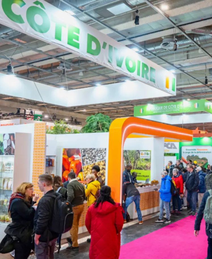 personnes déambulant dans les allées d'un salon devant le stand Côte d'Ivoire