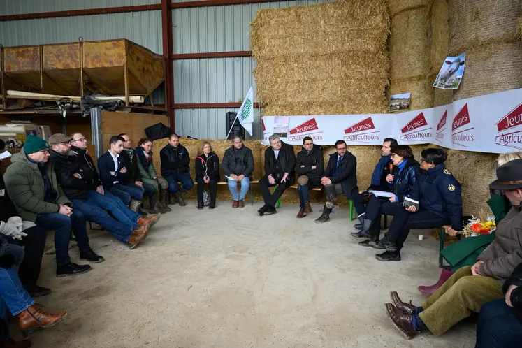 La ministre de l'Agriculture Annie Genevard assise devant de la paille sur une exploitation ovine en Haute-Marne, avec des représentants syndicaux des Jeunes agriculteurs et de la FNSEA.