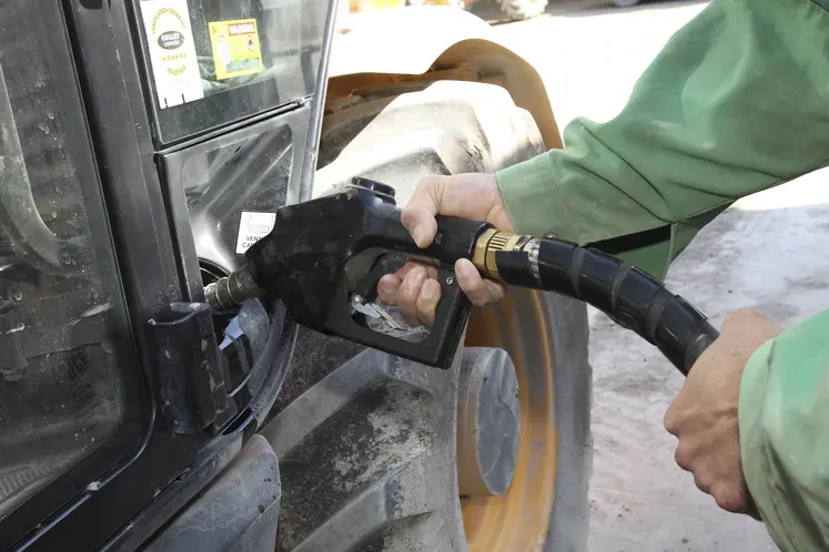 agriculteur tenant un pistolet pour faire le plein de son tracteur
