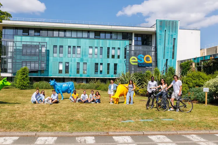étudiant posant devant un bâtiment scolaire où est mentionné ESA