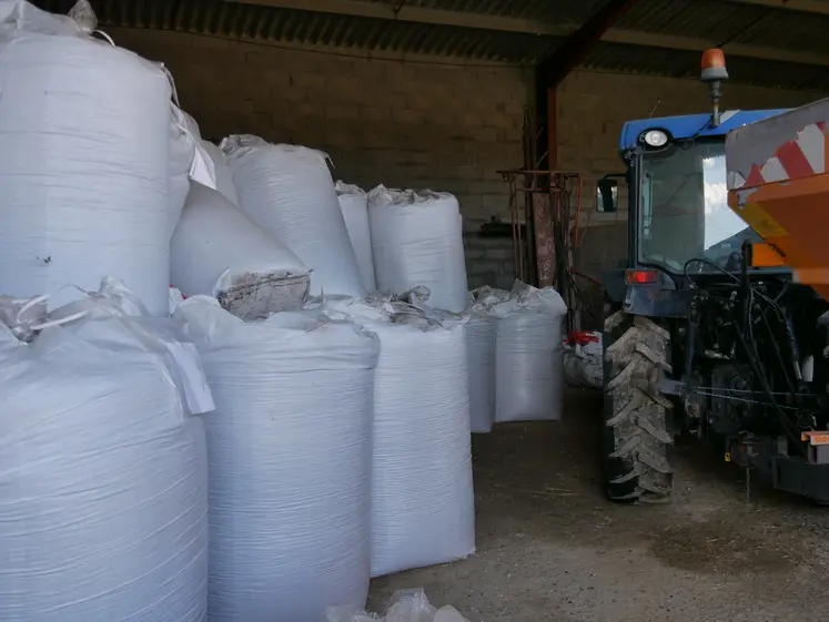 des sacs d'engrais et un tracteur entreposés dans un hangar agricole