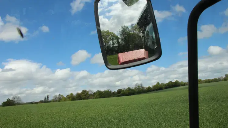 Champ de blé depuis la cabine d'un tracteur avec le rétroviseur visible. 