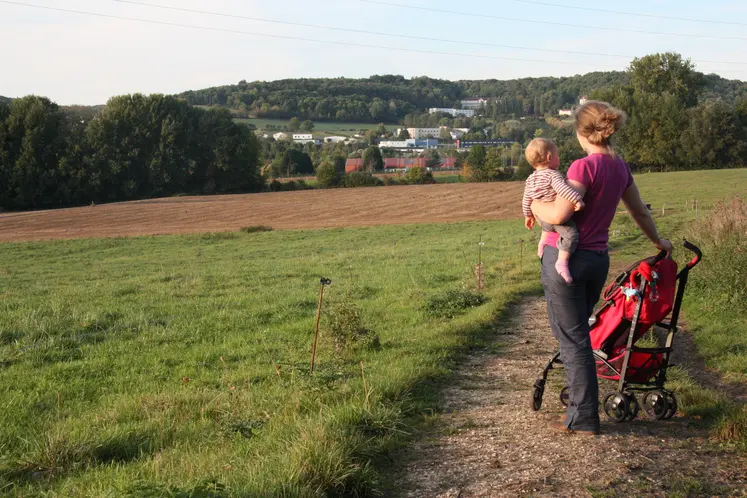   Femme avec son bébé dans les bras en promenade dans les champs  