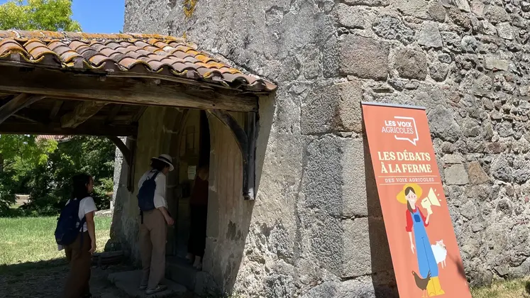 Panneau des "débats à la ferme" de l'association Les Voix Agricoles lors de la journée chez Nicolas Clair dans la Loire, avec derrière l'entrée de la chapelle Saint-Sulpice. 