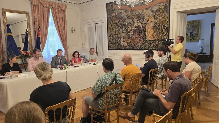 u  groupe de personnes assis derrière une table répondant à des journalistes