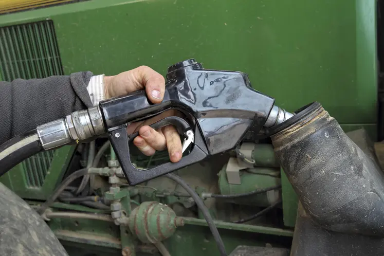  Main sur un pistolet de carburant au-dessus du réservoir d’un tracteur.