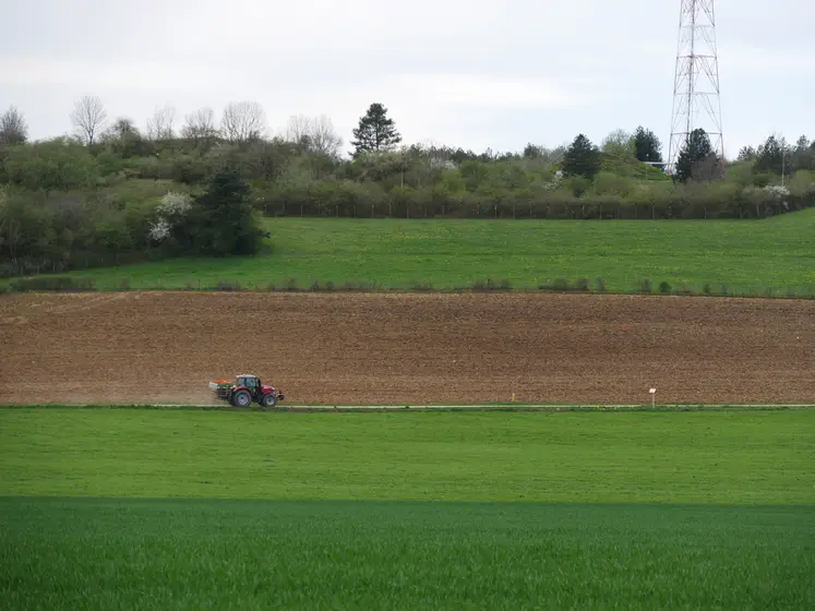 Paysage de zone intermédiaire au printemps, avec un tracteur dans un champ.