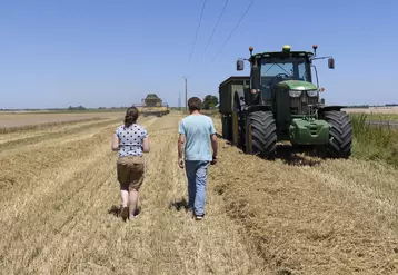 Deux agriculteurs de dos dans un champ de céréales à côté d'un tracteur