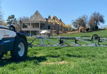 Pulvérisateur dans un champ avec maison en construction à l'arrière