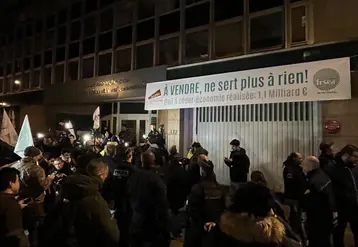 Des agriculteurs au petit matin devant l'Inrae sous une banderole avec l'inscription "à vendre, ne sert plus à rien"