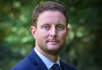 Clément Beaune, Haut-Commissaire à la stratégie et au plan, en gros plan devant un fond de verdure.