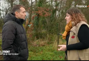 Hugo Clément discuant avec une éleveuse dans une prairie devant une haie.