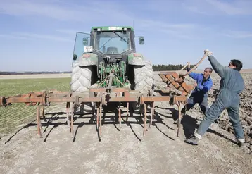 Deux agriculteurs mettant en place une herse de 4 mètres pour préparer les bords de champs    