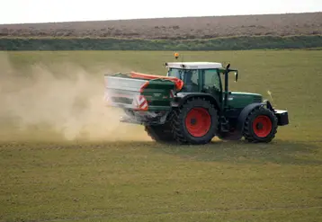Un tracteur épand un engrais azoté (ammonitrate) sur un champ de céréales. 