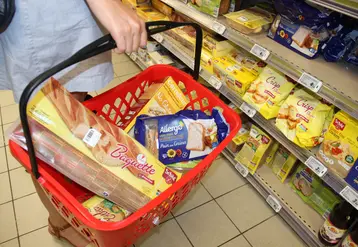 personne tenant un panier de courses dans un supermarché