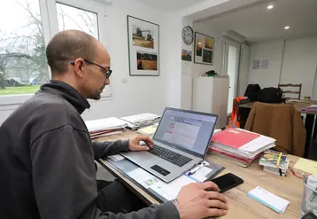 Un homme assis devant un ordinateur portable sur un bureau