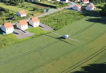 vue aérienne de maisons bordant des champs traités pas un tracteur 