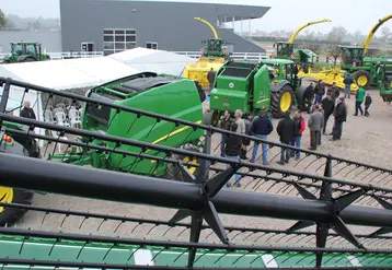 Visiteurs dans un concessionnaire John Deere devant des machines agricoles. 