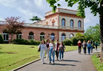 des élèves marchent sur une allée avec un bâtiment en briques en arrière-plan