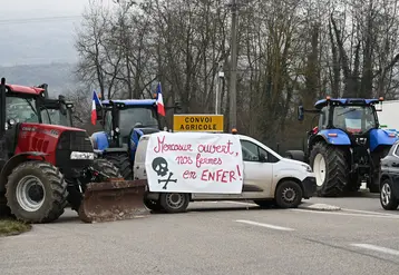Tracteurs bloquant une route, avec une banderole sur une voiture "Mercosur ouvert, nos fermes en enfer"