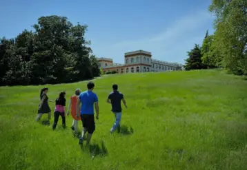 Jeunes gens courant dans l'herbe avec en fond une vieille bâtisse