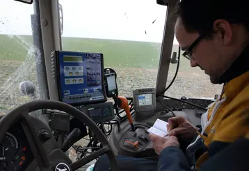 Agriculteur dans son tracteur notant dans son carnet les traitements phyto réalisés.