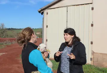 deux femmes qui discutent dont une tient un petit mouton dans les bras