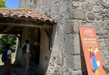 Panneau des "débats à la ferme" de l'association Les Voix Agricoles lors de la journée chez Nicolas Clair dans la Loire, avec derrière l'entrée de la chapelle Saint-Sulpice. 